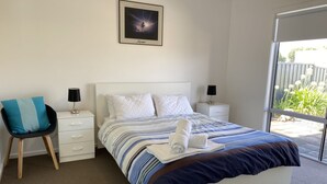 A neatly arranged bedroom with a bed, two bedside tables, a chair, and a window.