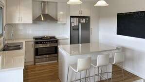 A modern kitchen with white cabinets, stainless steel appliances, and a central island with bar stools.