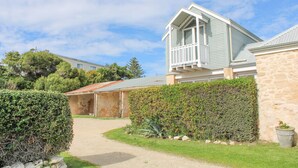 A two-story house with a balcony, a stone wall, and a well-maintained garden.