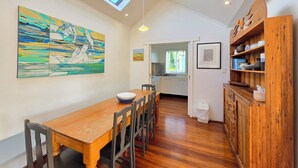 A dining area with a wooden table and chairs, a skylight, and a kitchen in the background.