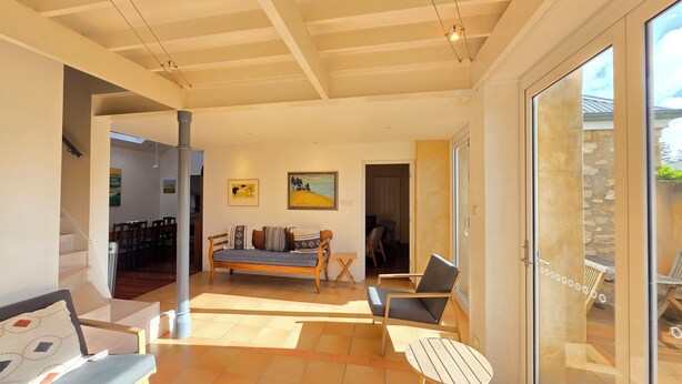 A spacious living area with a sofa, chairs, a small table, and a view through a glass door.