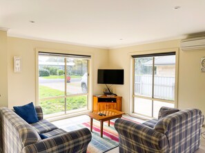 Relax in this cozy living space with a large window offering a view of the outdoors, a TV, and comfortable sofas.