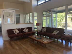 Relax in this stylish living room with a large window offering a view of the outdoors, two sofas, a coffee table, and a side table with a lamp.