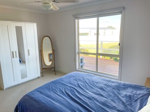 Relax in this serene bedroom with a large bed, a stylish wardrobe, and a ceiling fan. Enjoy the view from the large window.