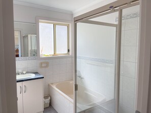 Bathroom features a white sink, bathtub, and glass shower enclosure.