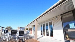 A modern building with a covered deck area featuring outdoor seating. - Latitude 37 - Large expansive deck - Pets Welcome - Outside Only (Robe)