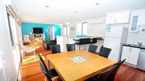 A modern kitchen with white cabinets, a built-in oven, and a dining area with a wooden table and black chairs. - Latitude 37 - Large expansive deck - Pets Welcome - Outside Only (Robe)