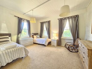 A bedroom with two beds, a dresser, a chair, and a window with curtains. - Stone Cottage - Gorgeous cottage charm, in the heart of Robe Town (Robe)