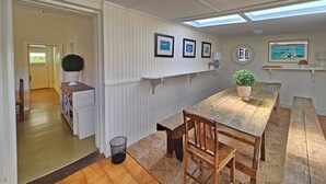 Un coin repas avec une table et des chaises en bois, une plante en pot et des œuvres d’art encadrées accrochées au mur.