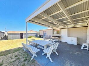 A covered patio with a table and benches, a grill, and a storage cabinet. - Stone Cottage - Gorgeous cottage charm, in the heart of Robe Town (Robe)