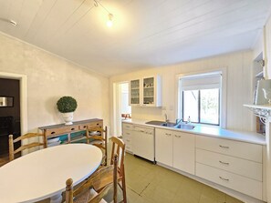 A kitchen with white cabinets, a round dining table, and wooden chairs.