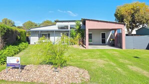 A modern two-story building with a glass facade, a covered patio, and a sign indicating a rental property. - Sun on Sanders - Modern 2 br house close to main street. Pet Friendly Outside (Robe)