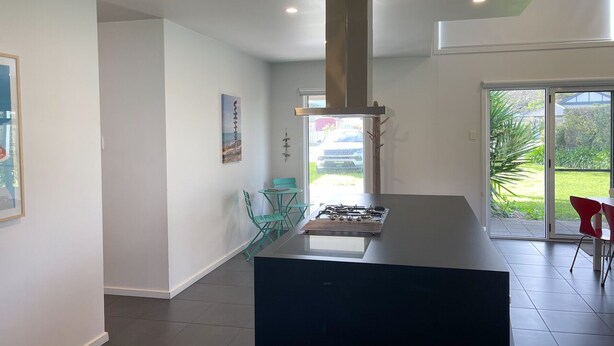 A modern kitchen with a central island, a gas stove, and a large window overlooking a garden. - Sun on Sanders - Modern 2 br house close to main street. Pet Friendly Outside (Robe)