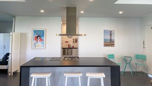 A modern kitchen with a central island, recessed lighting, and a view into the dining area with chairs. - Sun on Sanders - Modern 2 br house close to main street. Pet Friendly Outside (Robe)
