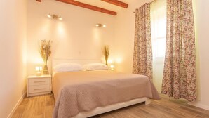 Een slaapkamer met een bed, nachtkastjes en een raam met bloemen gordijnen.