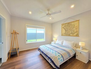 A bedroom with a bed, a standing lamp, a map on the wall, and a window. - Bells On Frome - Coastal shutters, wood fire and the coastal charm. (Robe)