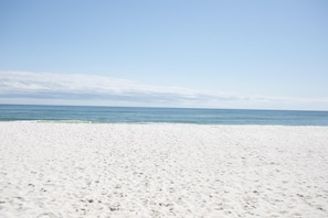 Une plage de sable blanc, bordée par une mer calme sous un ciel dégagé.