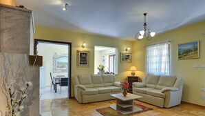 A living room with two sofas, a coffee table, and a chandelier. There is a dining area visible through an open door. - Comfortable villa with private pool near sandy beach (Medulin)