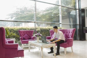 Un espacio interior moderno con ventanas amplias, una mesa de centro de cristal y sillones tapizados en color púrpura.