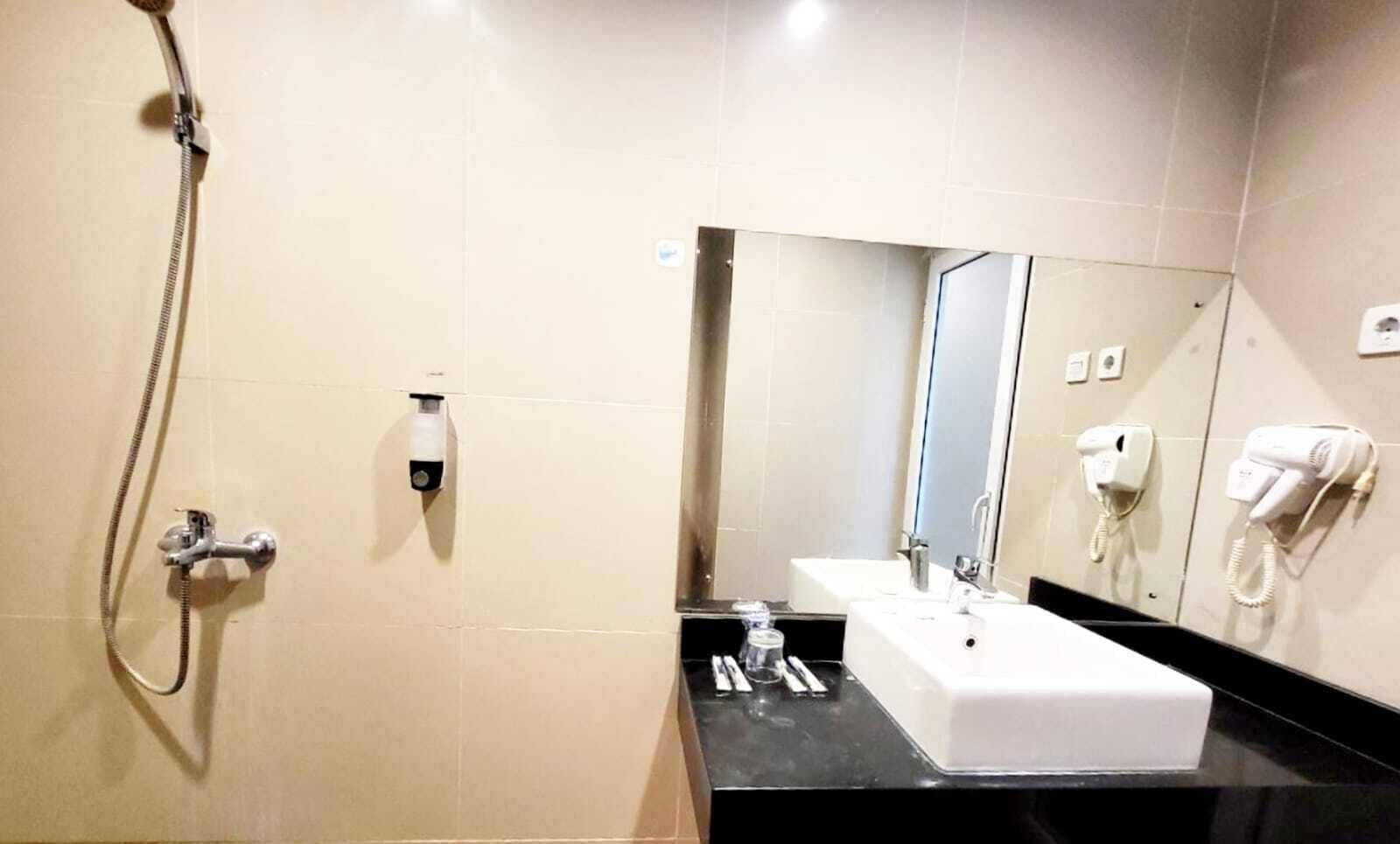 A bathroom with a shower, a sink, a mirror, and a hairdryer on the wall.