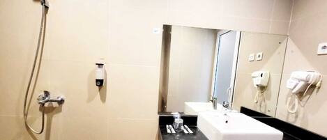 A bathroom with a shower, a sink, a mirror, and a hairdryer on the wall.
