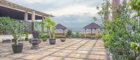 A courtyard with a tiled floor, potted plants, and a wooden pergola.