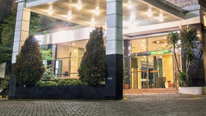 Un hotel con un cartel llamativo, un acceso cubierto y fachada de ladrillo.