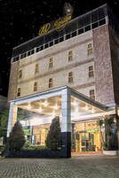 Um hotel com uma placa visível, entrada coberta e fachada de tijolos.