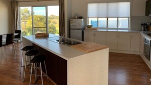 A modern kitchen with a central island, bar stools, a refrigerator, and a view of the outdoors. - Blauhaus - Relax all your blues away... (Robe)