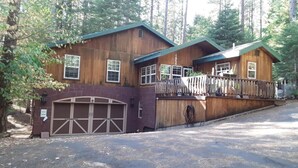 Eine zweistöckige Holzhütte mit Veranda und Garage.