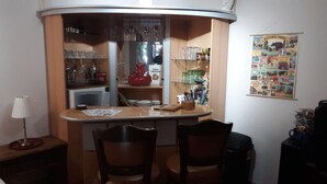 Eine kompakte Küche mit einer zentralen Kochinsel, Holzstühlen und einem kleinen Kühlschrank.
