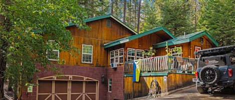 A cabin with a garage, a covered porch, and a vehicle parked in front.