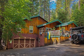 Une cabane avec un garage, une véranda et un véhicule garé devant.