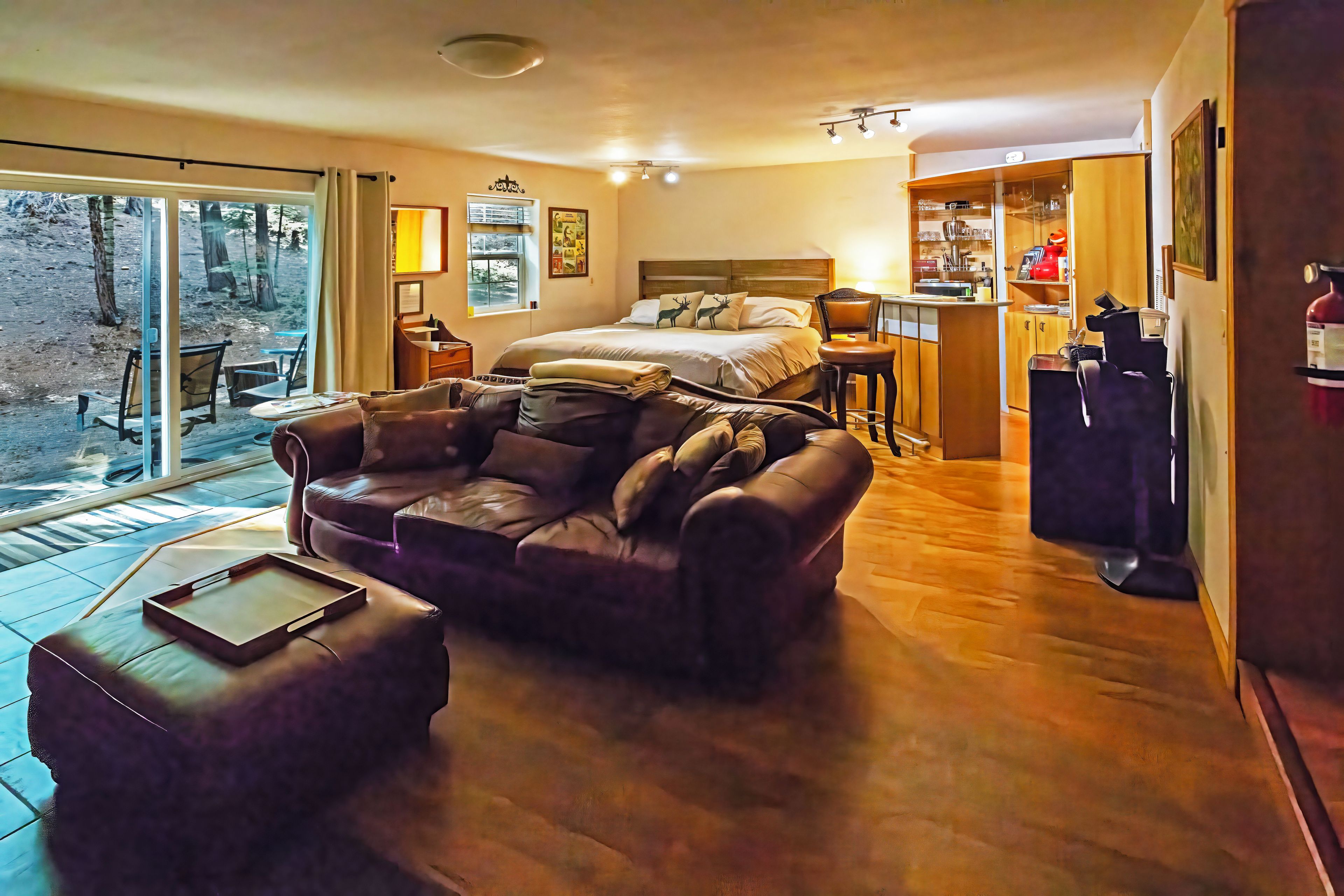 A cozy room with a bed, a sofa, a dining area, and a view of the outdoors.