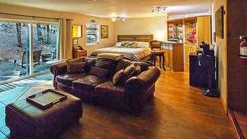 A cozy room with a bed, a sofa, a dining area, and a view of the outdoors.