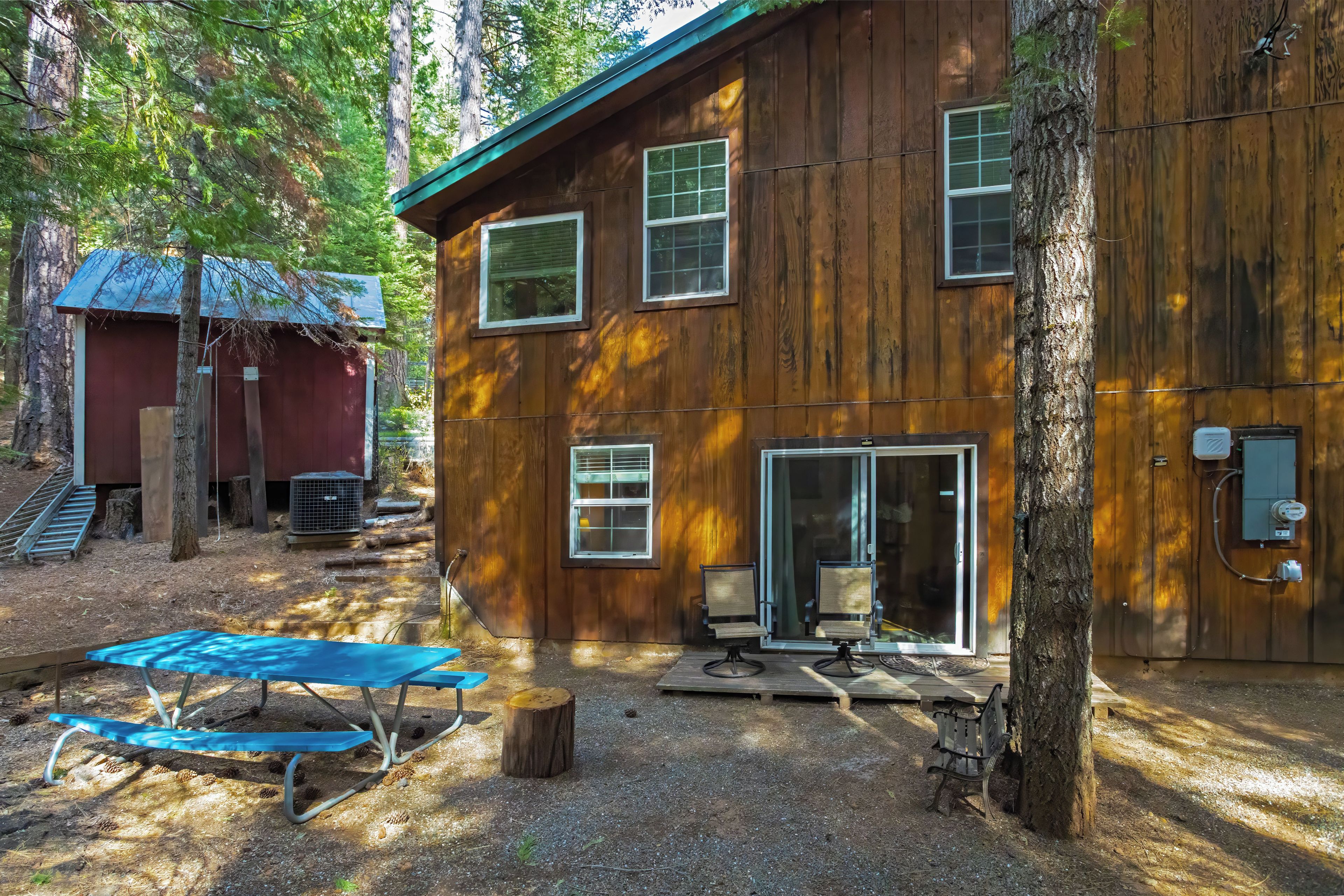 A wooden cabin with a covered patio, a small deck, and a large window.