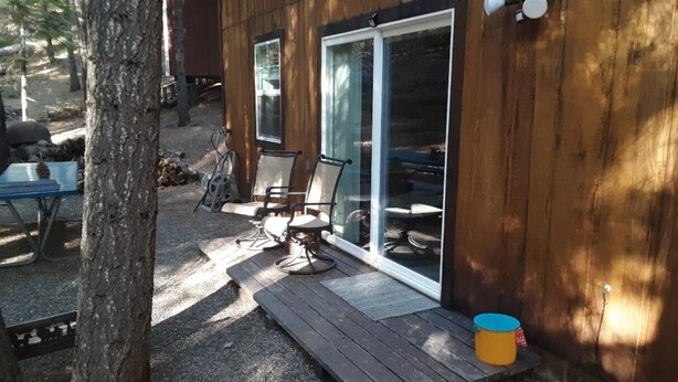 Eine Holzhütte mit einer Veranda, Sitzgelegenheiten im Freien und einer Schiebetür.