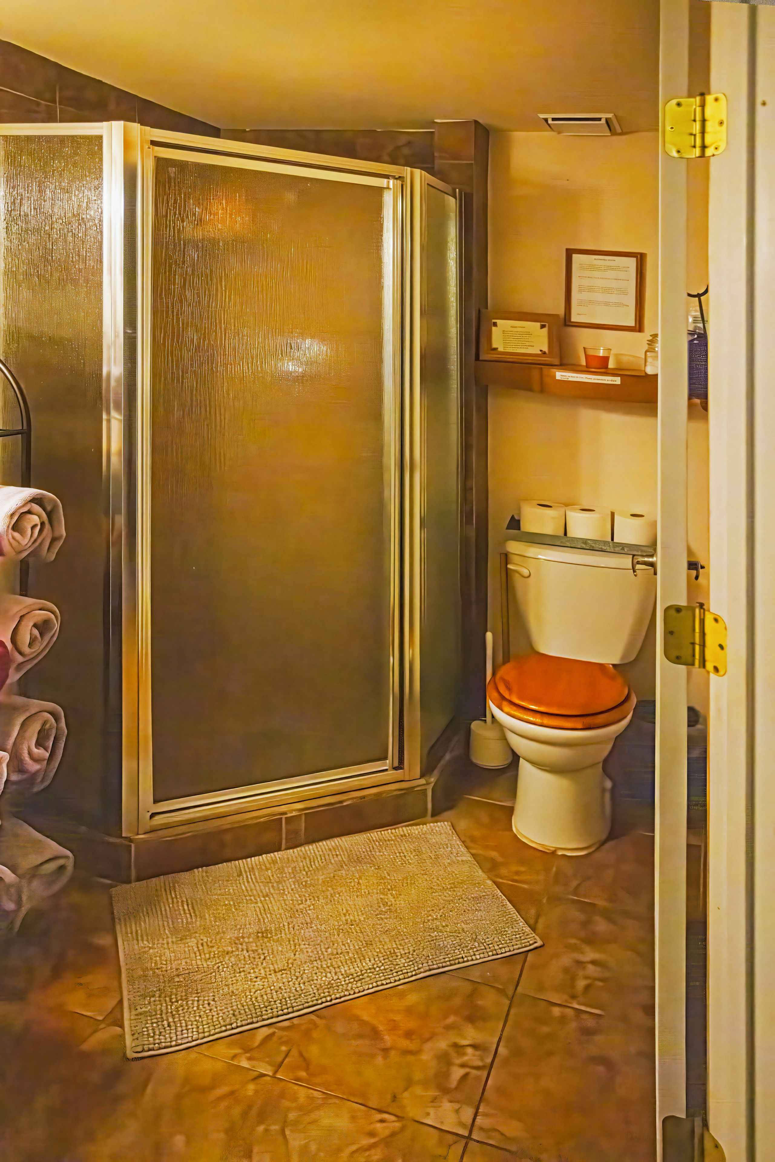 A bathroom with a shower enclosure, toilet, and a small shelf with toiletries.
