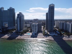 A high-rise hotel with a swimming pool and a beach view.