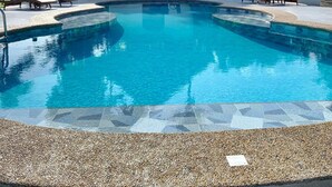 Ein Schwimmbecken mit Liegestühlen und einer Struktur mit Reetdach.