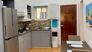Eine moderne Küche mit Backofen, Wasserspender und Essbereich mit Tisch und Stühlen.