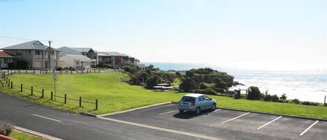 A parking lot with a car, a grassy area, and buildings in the background.