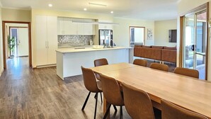 Eine moderne Küche mit weißen Schränken, einer zentralen Kochinsel und einem Essbereich mit Holztisch und -stühlen.