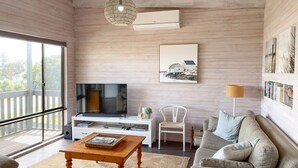 Una sala de estar con televisión, sofá y mesa de centro.