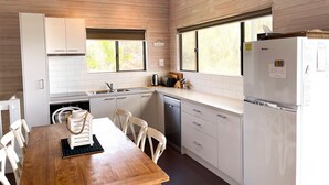 Una cocina funcional con muebles blancos, una mesa de comedor de madera y un refrigerador.