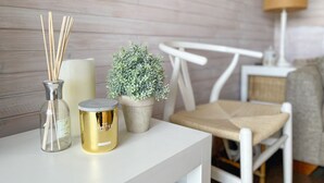 Una mesa blanca con una vela, una planta pequeña en maceta y un candelabro decorativo.