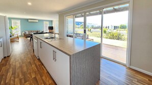 A modern kitchen with a large island, sliding glass doors to a patio, and a view of the neighborhood.