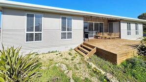 A modern single-story house with a covered patio, a barbecue area, and a small deck.