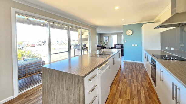 A modern kitchen with a large island, sliding glass doors, and a view of the outside.
