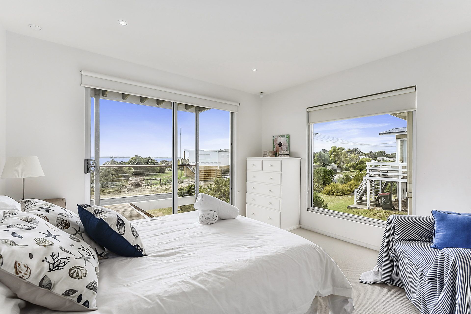 Une chambre avec un grand lit, une commode et une vue sur un pont et la verdure.